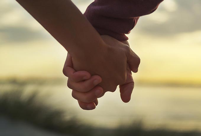 Couple in a positive relationship, walking holding hands on the beach