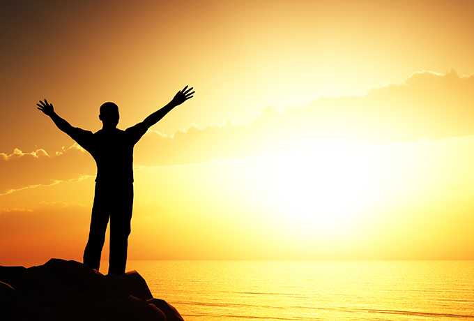 Man standing with his arms wide welcoming the sunrise