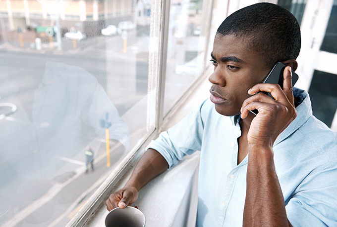Man on phone looking out a window